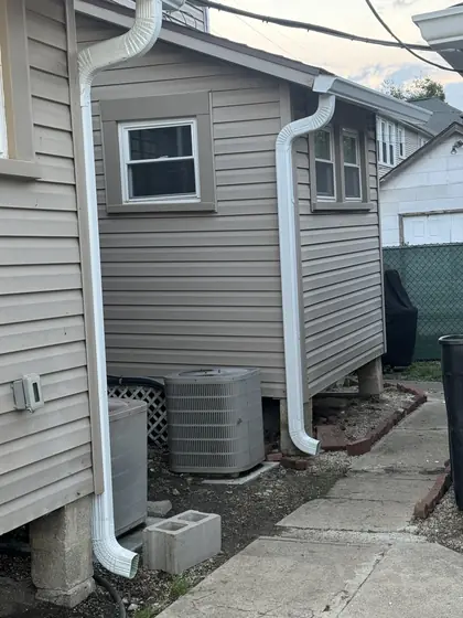 New white downspout running neatly down tan siding