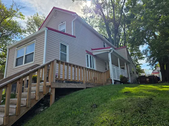 Two-tone house with new white seamless gutters above a deck